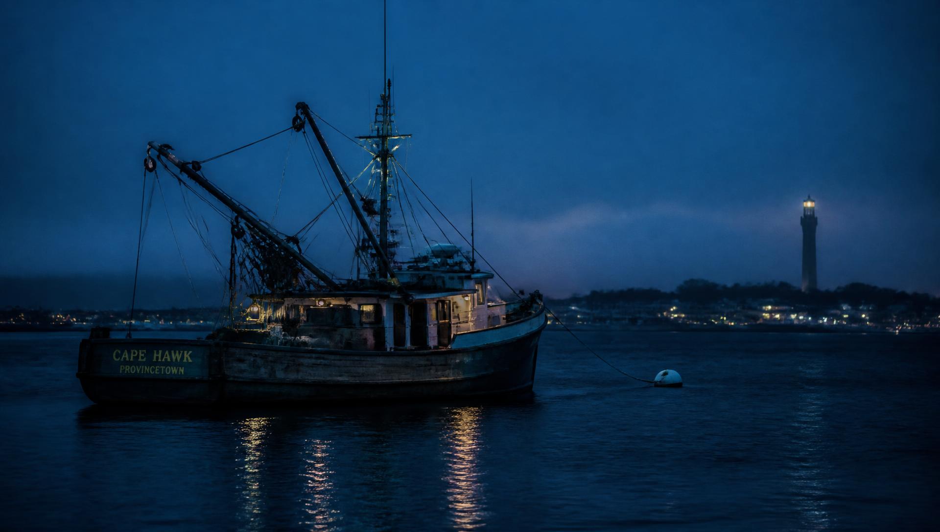 A wooden fishing dragger moored in Provincetown harbor at nautical twilight